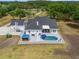 Aerial view of the rear of a home, pool, gazebo, and patio with ample seating, landscaped backyard, and driveway at 6824 283Rd E St, Myakka City, FL 34251