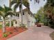 Two-story home with two-car garage and red brick driveway nestled among lush palm trees at 770 Yale St, Englewood, FL 34223