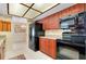 Well-lit kitchen with cherry wood cabinetry, modern black appliances and tiled flooring, offering a functional design at 810 Anchorage Ln, Palm Harbor, FL 34685