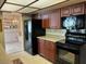 Well-lit kitchen with cherry wood cabinetry, modern black appliances and tiled flooring, offering a functional design at 810 Anchorage Ln, Palm Harbor, FL 34685
