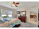 Bright bedroom featuring ceiling fan, gray carpet, dresser with mirror, and a glimpse into the adjacent living room at 8997 Excelsior Loop, Venice, FL 34293