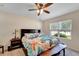 Comfortable bedroom with a ceiling fan, a large bed with decorative pillows, and a window providing natural light at 8997 Excelsior Loop, Venice, FL 34293