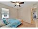 Comfortable bedroom with a ceiling fan, window, beach-themed bedding, and a door at 8997 Excelsior Loop, Venice, FL 34293