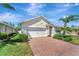 Charming single-story home with a manicured lawn, brick driveway, and a two-car garage at 8997 Excelsior Loop, Venice, FL 34293