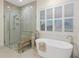 Bright bathroom featuring walk-in shower and modern soaking tub under shuttered window at 9810 Eagle Preserve Dr, Englewood, FL 34224