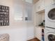 Neat laundry room featuring a stacked washer and dryer, storage cabinets and plantation shutters at 9810 Eagle Preserve Dr, Englewood, FL 34224