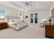 Bright main bedroom featuring a tray ceiling, private balcony access, and neutral decor at 9810 Eagle Preserve Dr, Englewood, FL 34224