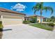 Home exterior view featuring a two-car garage, driveway, and manicured tropical landscaping at 11186 Batello Dr, Venice, FL 34292