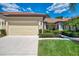 Home exterior featuring a tan two-car garage, driveway, and well-maintained landscaping at 11186 Batello Dr, Venice, FL 34292