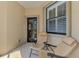 Cozy covered patio with two comfortable chairs, a window with shutters, and a view into the home at 11186 Batello Dr, Venice, FL 34292