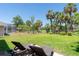 Spacious backyard featuring a lush lawn, tall palms, and lounge chairs for relaxing outdoors at 1124 W Hillsborough Blvd, North Port, FL 34288