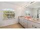 Bright bathroom showcasing dual sinks, granite countertops, a large mirror, and natural light at 113 Mark Twain Ln, Rotonda West, FL 33947