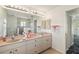 Bright bathroom showcasing dual sinks, granite countertops, and a large mirror with vanity lighting at 113 Mark Twain Ln, Rotonda West, FL 33947