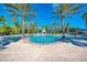Stunning community pool surrounded by swaying palm trees, lounge chairs, and clear blue skies at 11437 Dancing River Dr, Venice, FL 34292