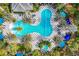 Overhead shot of a large pool with a checkerboard-tiled patio surrounded by palm trees and blue umbrellas at 11455 Fort Lauderdale Pl, Venice, FL 34293