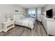 Bright bedroom with floral bedding, light wood floors, and direct access to the balcony at 1150 Tarpon Center Dr # 3G 307, Venice, FL 34285