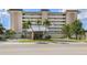 Elegant multi-story condo building featuring well-manicured landscaping and a charming entrance area with an American flag at 1150 Tarpon Center Dr # 3G 307, Venice, FL 34285