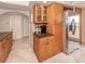 Functional kitchen area with wooden cabinetry, stainless steel refrigerator, and adjacent pantry at 1150 Tarpon Center Dr # 3G 307, Venice, FL 34285