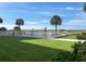Inviting pool area surrounded by lush green grass, palm trees, and a glimpse of the ocean at 1150 Tarpon Center Dr # 3G 307, Venice, FL 34285