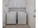 Functional laundry room featuring a side-by-side washer and dryer with overhead storage cabinets at 11610 Dancing River Dr, Venice, FL 34292