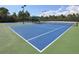 Bright blue tennis court with green surround, net and canopy, ready for a match at 11610 Dancing River Dr, Venice, FL 34292