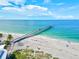 Scenic aerial view of a long fishing pier stretching into the ocean with people on the beach at 11711 Alessandro Ln, Venice, FL 34293