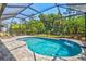 Beautiful screened-in pool with waterfall feature and ample space for lounging in a tropical setting at 11711 Alessandro Ln, Venice, FL 34293