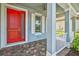 Cozy front porch featuring brick flooring, stylish columns, and a vibrant red front door at 11711 Alessandro Ln, Venice, FL 34293