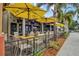 Outdoor dining patio with umbrellas, tables, and chairs alongside a sidewalk at 11711 Alessandro Ln, Venice, FL 34293