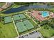 Aerial view of tennis courts, community pool, clubhouse, lake, and neighborhood at 12515 Felice Dr, Venice, FL 34293