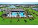 Aerial shot highlighting a large community pool with sun loungers and palm trees, set against a backdrop of homes and lake at 12897 Oriago St, Venice, FL 34293