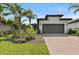 Inviting home with a two car garage, brick driveway, lush landscaping, and a well-manicured lawn at 12897 Oriago St, Venice, FL 34293