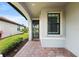 Inviting front porch with brick flooring, leads to a modern home with well-maintained landscaping and a window at 12897 Oriago St, Venice, FL 34293