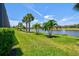 Lush backyard featuring a serene lake view and tropical palm trees at 13202 Borrego St, Venice, FL 34293
