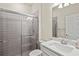 Well-lit bathroom features a sleek glass shower with grey horizontal tiling, and a single sink at 13202 Borrego St, Venice, FL 34293