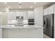 Well-lit modern kitchen with stainless steel appliances, island, and white cabinets, perfect for culinary enthusiasts at 13202 Borrego St, Venice, FL 34293