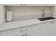 Clean kitchenette with white cabinets, light countertops, a stainless steel sink, and silver hardware at 13202 Borrego St, Venice, FL 34293