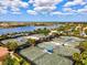 Aerial view of community tennis courts with lush landscaping, a lake, and beautiful skies at 13202 Borrego St, Venice, FL 34293
