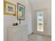 Bright foyer with a decorative glass door, white cabinet, tiled floor, and artwork at 13648 Clara Ln, Port Charlotte, FL 33981