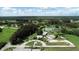 Expansive aerial view showcasing the home's landscaping, circular driveway, and tranquil pond surrounded by lush greenery at 140 Hermes Rd, Venice, FL 34293