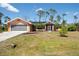 Single-story home with attached garage, lush lawn, and a walkway leading to the screened front entrance at 14124 Kewanee Ln, Port Charlotte, FL 33981
