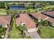 An aerial view of a home featuring solar panels, a lake and lush landscaping at 162 Palazzo Ct, North Venice, FL 34275
