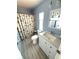 Clean bathroom with beach themed shower curtain, white sink vanity, and light colored wood floors at 175 Palm Harbor Dr, North Port, FL 34287