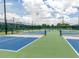 Multiple tennis courts with new surfaces surrounded by tall fences and greenery at 175 Palm Harbor Dr, North Port, FL 34287