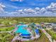 An aerial view of a resort-style community pool surrounded by palm trees, lounge chairs, and inviting blue umbrellas at 17515 Jadestone Ct, Venice, FL 34293