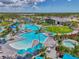 An aerial view of a resort-style pool with lounge chairs, palm trees, and blue umbrellas, perfect for relaxation and recreation at 17515 Jadestone Ct, Venice, FL 34293