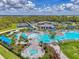 A bird's-eye view shows a luxurious community pool with vibrant blue umbrellas, tennis courts, and meticulously kept landscaping at 17515 Jadestone Ct, Venice, FL 34293
