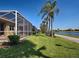 Landscaped backyard featuring a screened-in lanai with a water view at 19240 Isadora St, Venice, FL 34293