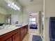 Bathroom featuring double sinks, wood cabinets, glass shower, and doorway to the main bedroom at 19240 Isadora St, Venice, FL 34293