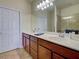 Bathroom featuring double sinks with wood cabinetry, a large mirror, and a tiled floor at 19240 Isadora St, Venice, FL 34293